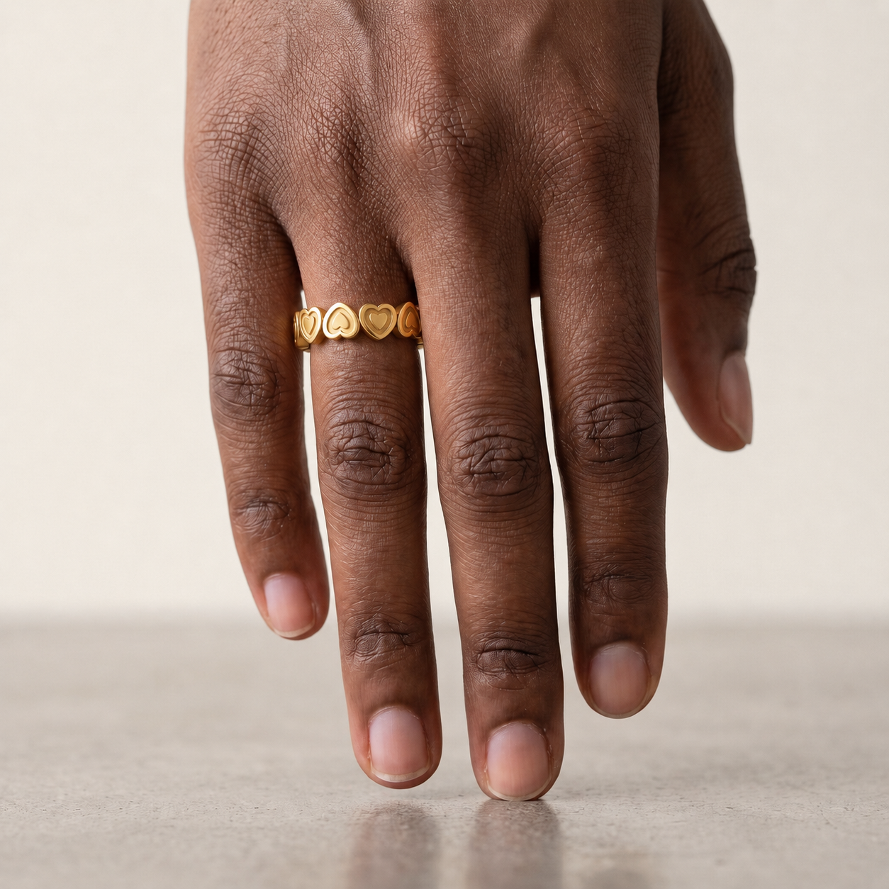 A gold heart-link ring shown worn on the hand.