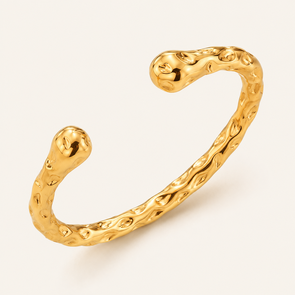 A textured gold open cuff bracelet with a wavy, organic shape and polished finish.