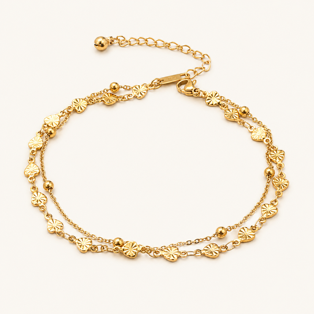 A gold-toned double-strand chain anklet decorated with small flower-shaped charms and polished beads.