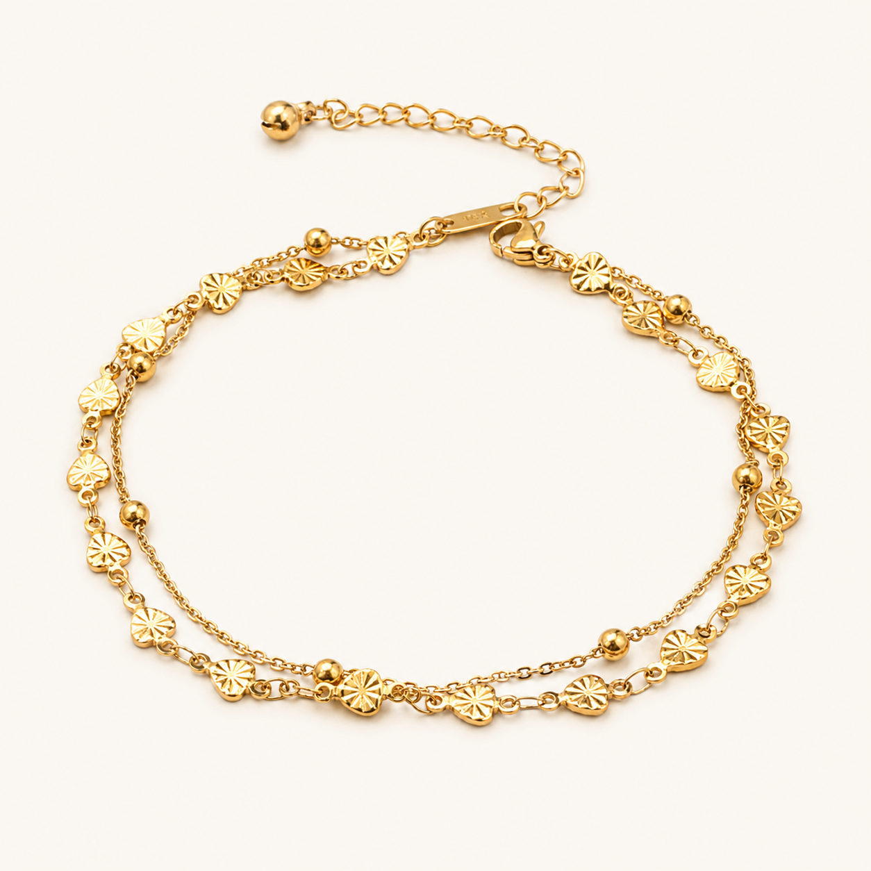 A gold-toned double-strand chain anklet decorated with small flower-shaped charms and polished beads.