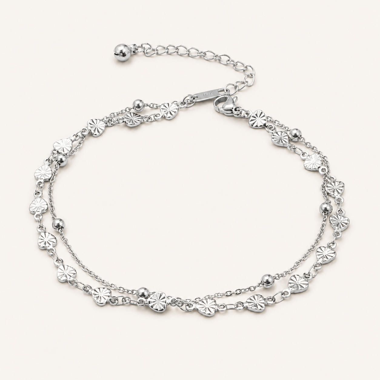 A silver-toned double-strand chain anklet decorated with small flower-shaped charms and polished beads.