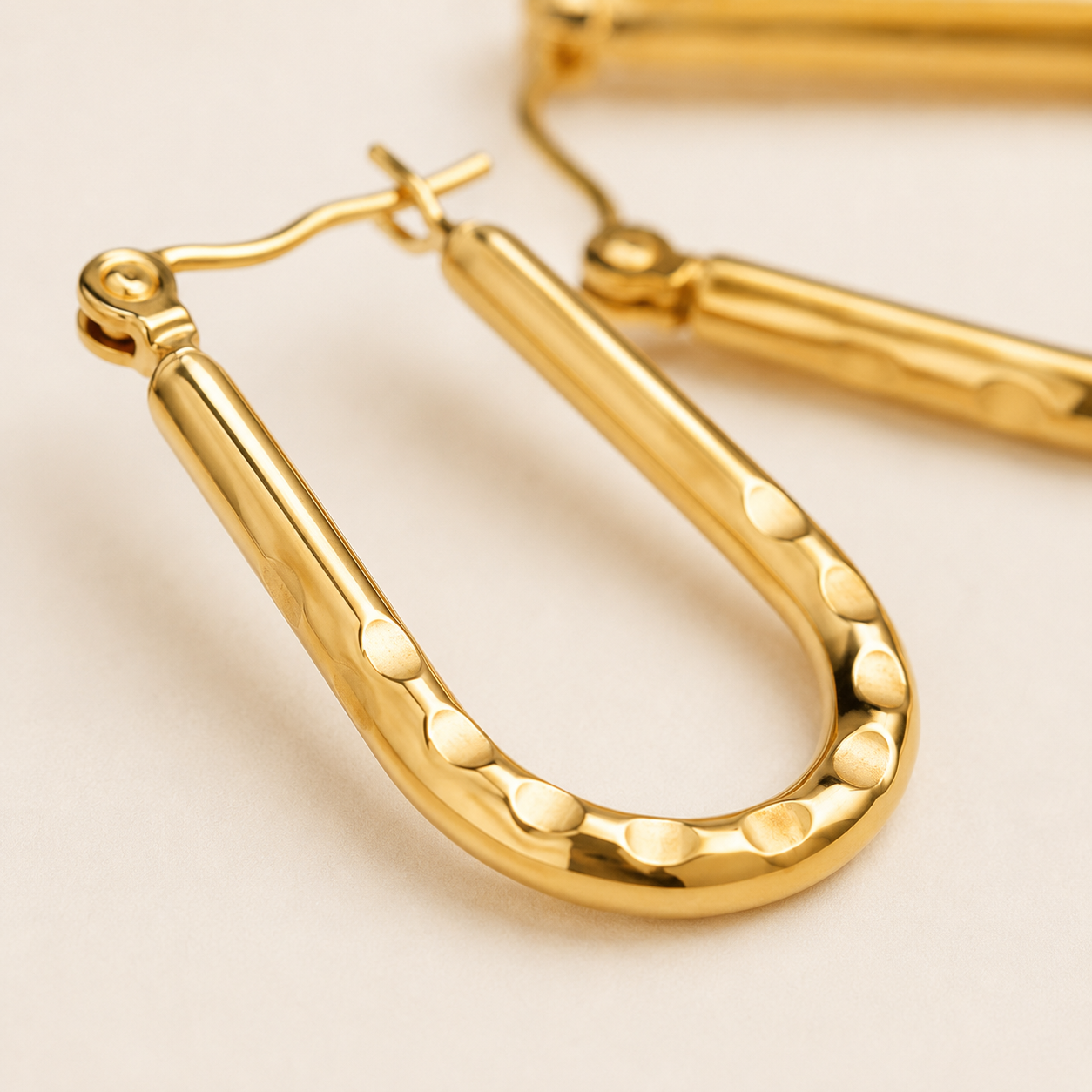 Gold u-shaped earrings with a hammered finish and fishhook backings.