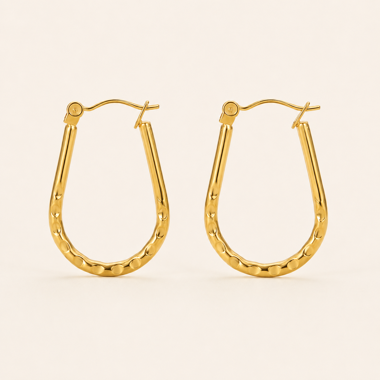 A pair of gold u-shaped earrings with a hammered finish and fishhook backings.