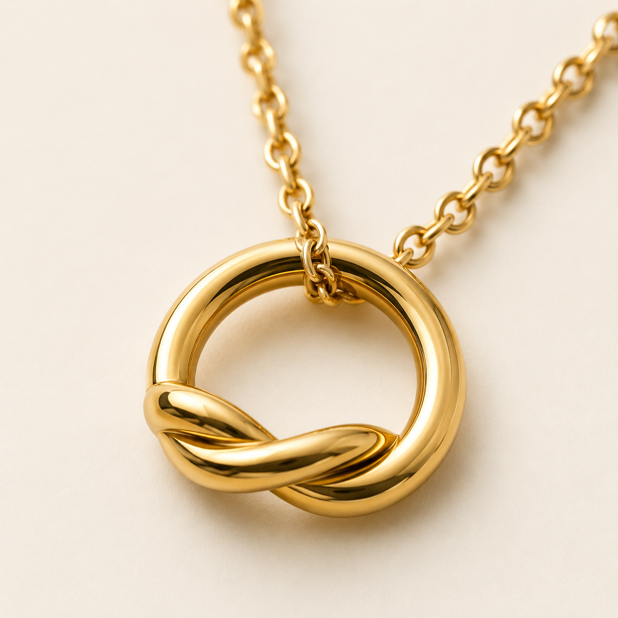 A polished gold necklace featuring a circular love-knot pendant.