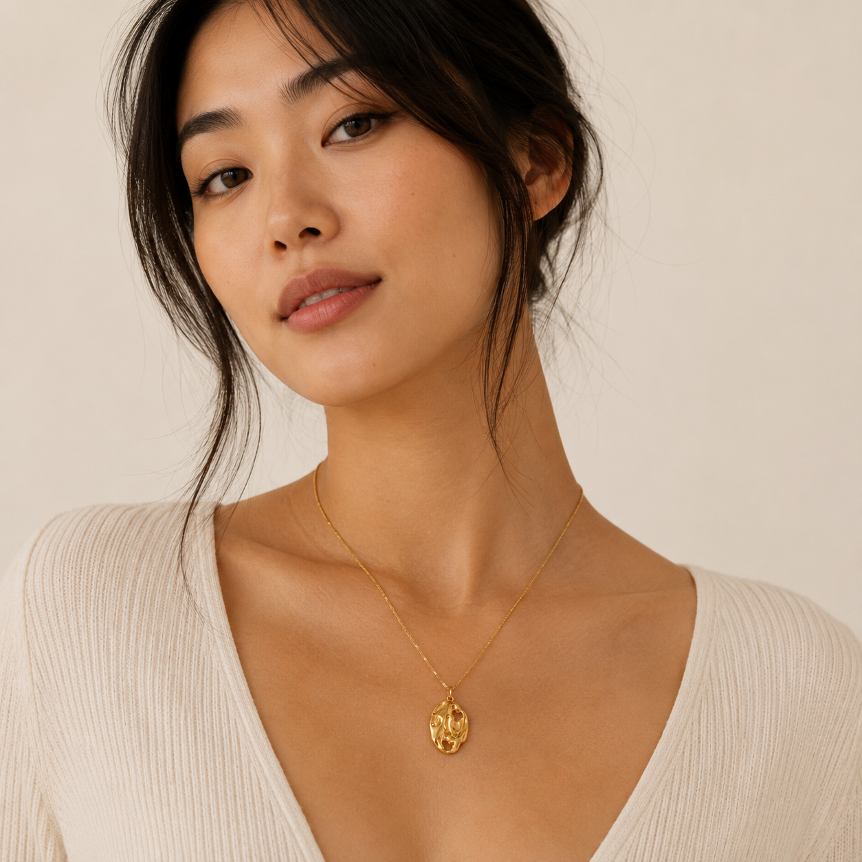 Model wearing gold delicate pendant necklace with a natural hammered look