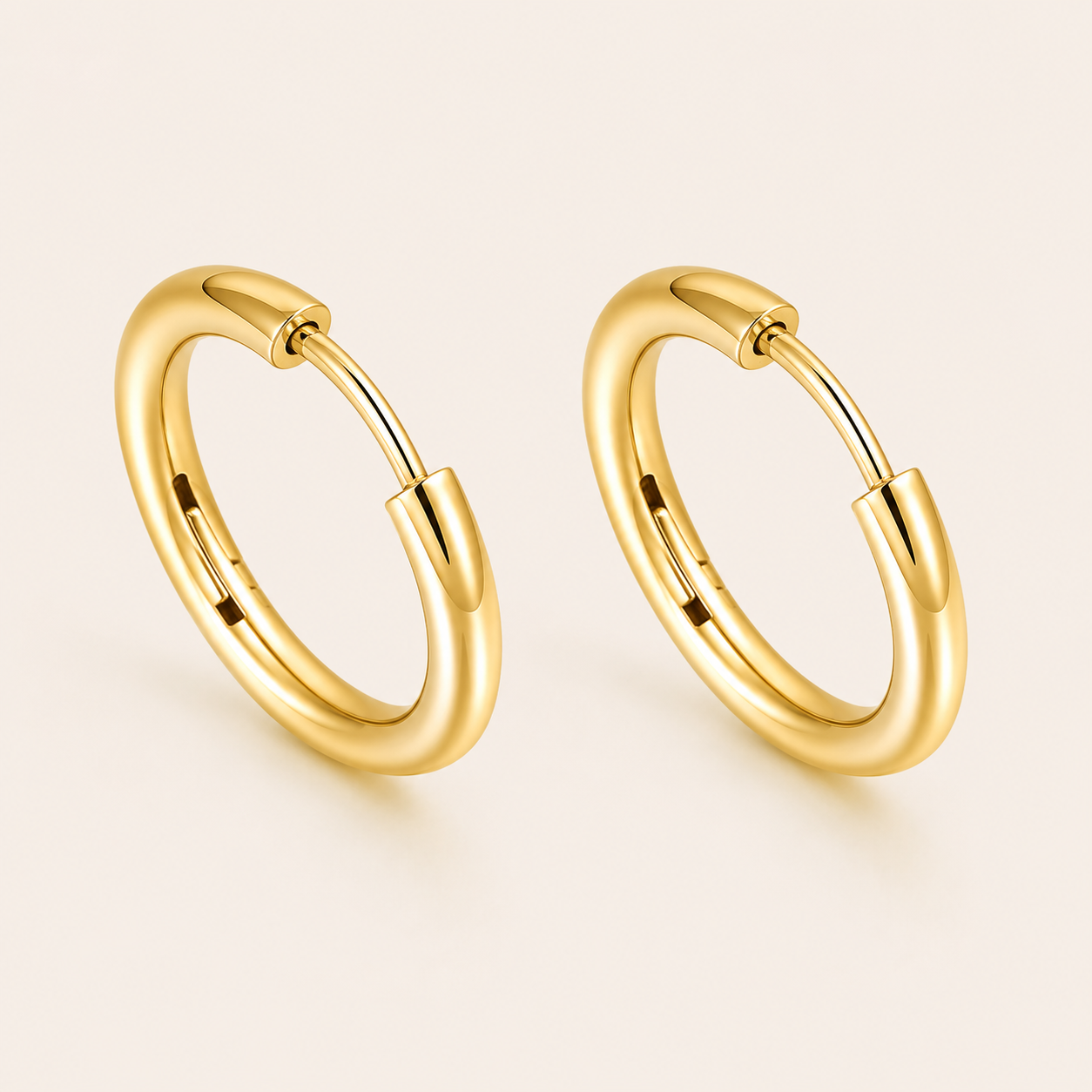 A pair of polished yellow gold huggie hoop earrings.