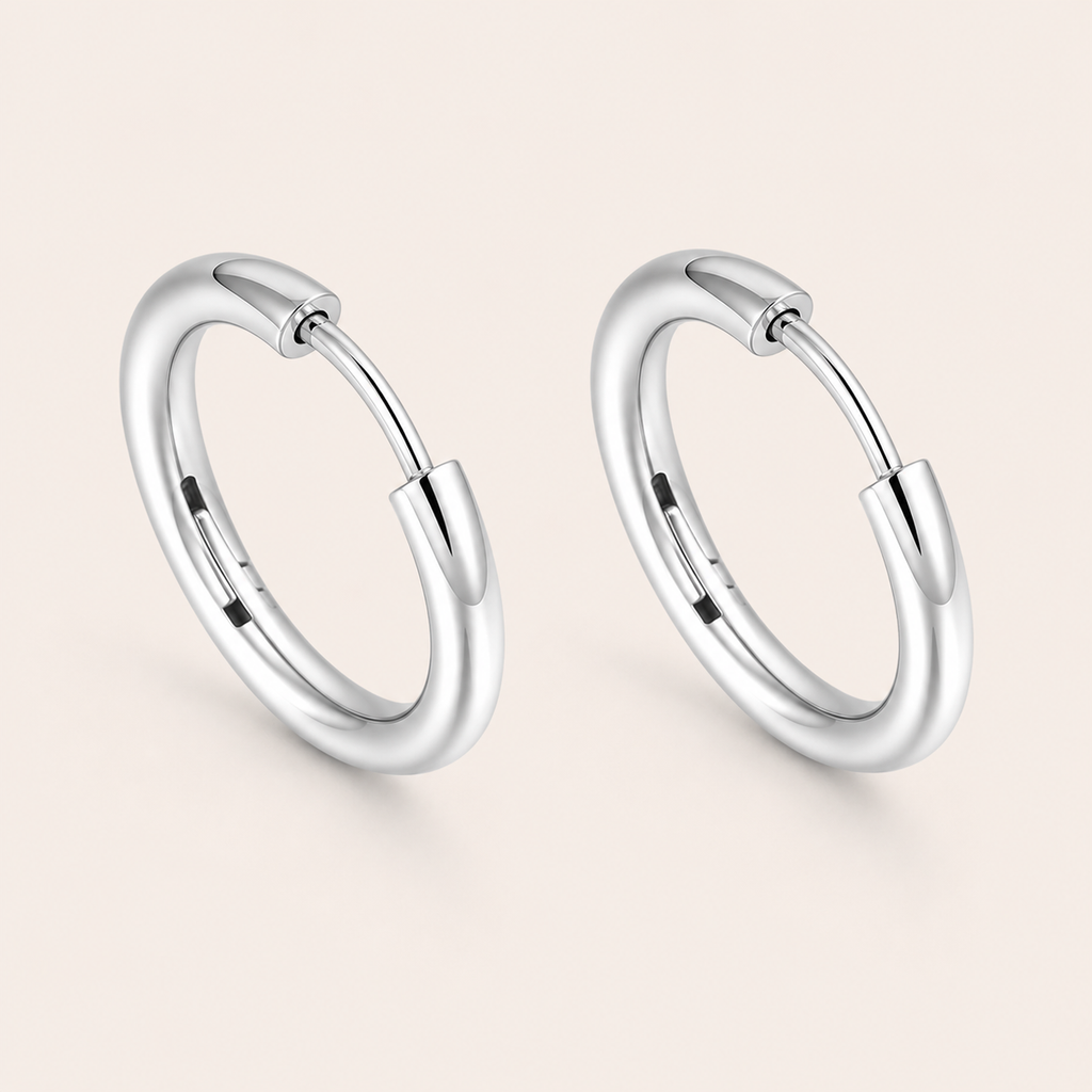 A pair of polished silver huggie hoop earrings.
