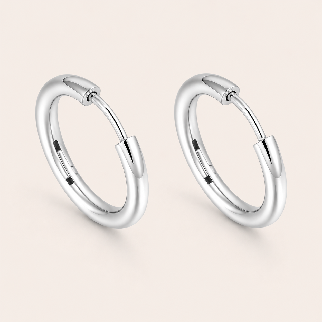 A pair of polished silver huggie hoop earrings.