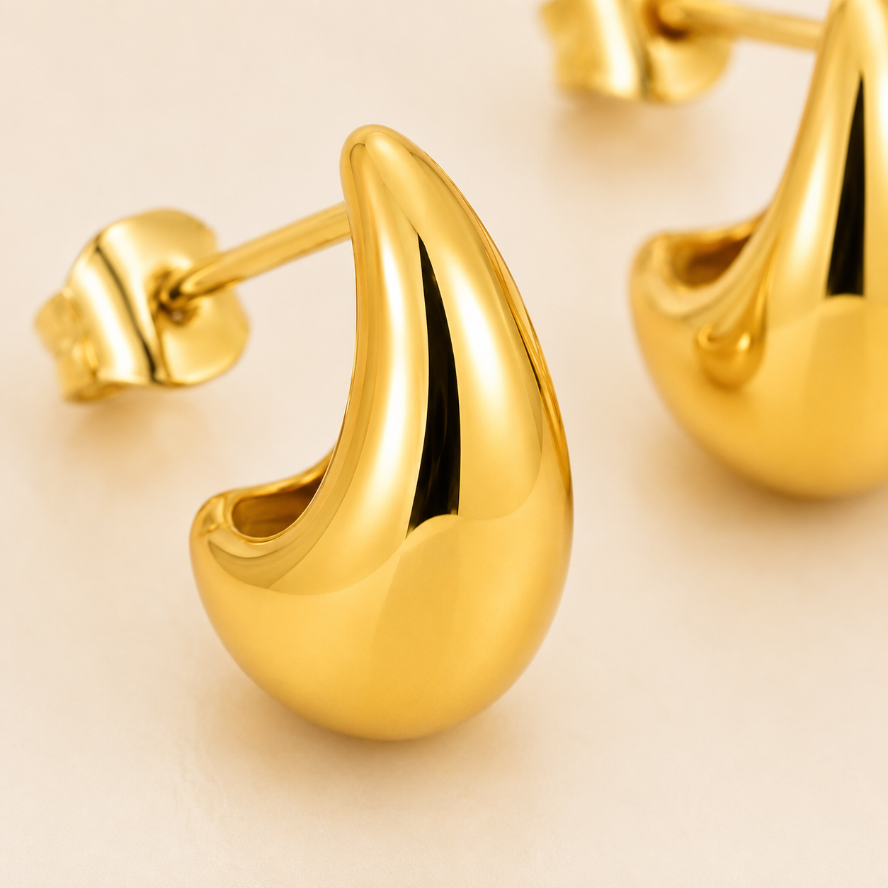 Close-up of polished gold crescent-shaped hoop earrings with post backs.