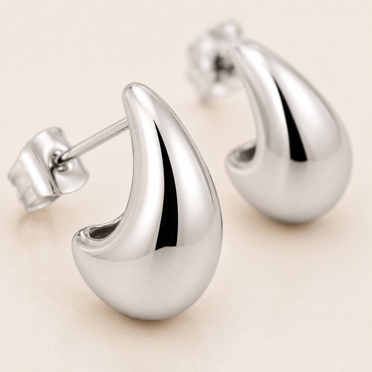 A pair of polished silver teardrop-shaped stud earrings with post-back closures.