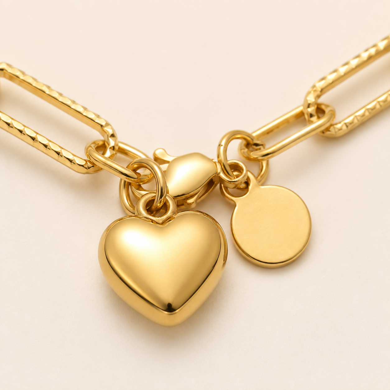 A gold-tone chain necklace featuring a polished heart-shaped charm and a flat round disc tag.