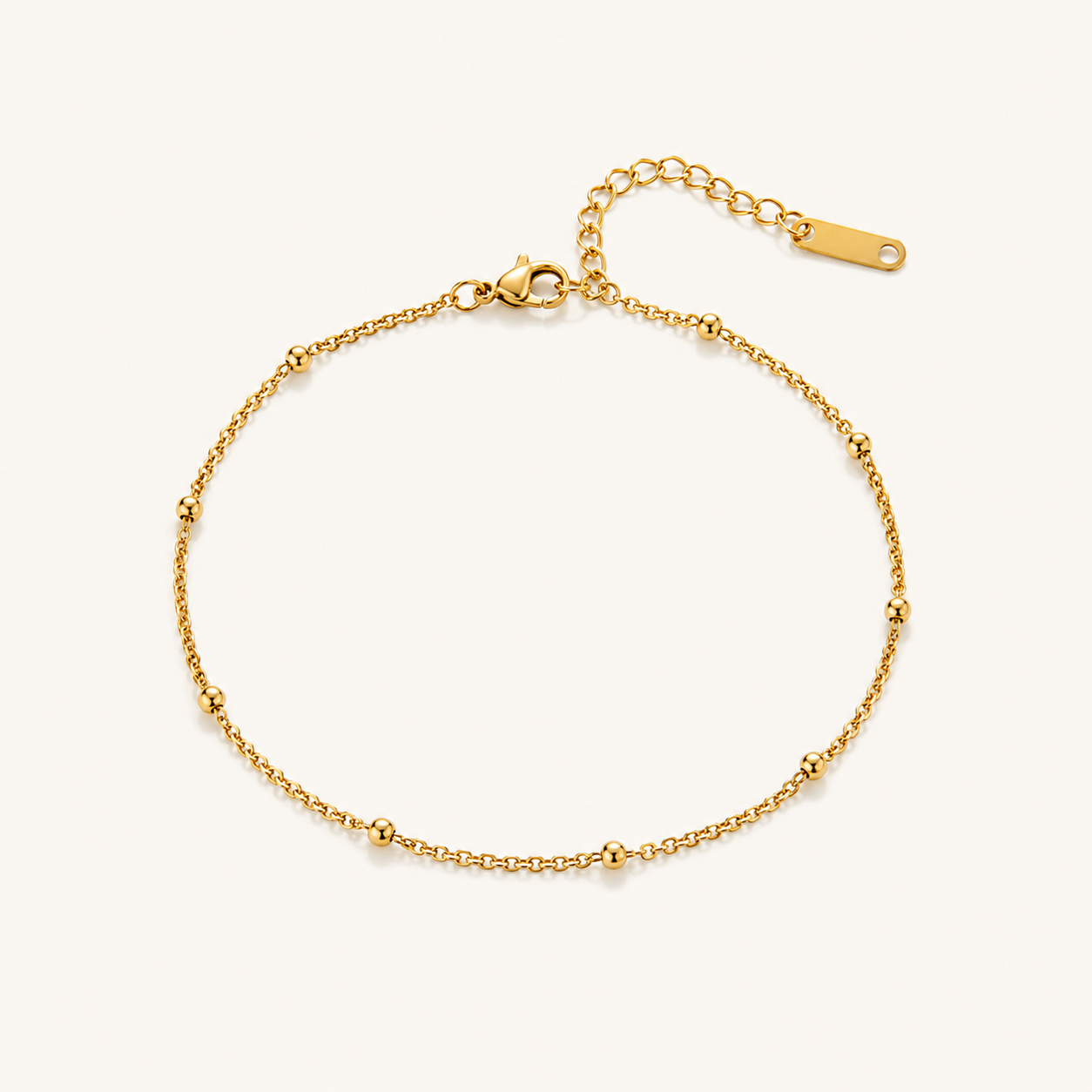 A delicate gold chain anklet with small bead accents along the chain.