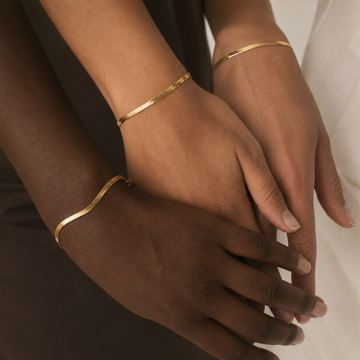Three gold herringbone chain bracelets shown on three different skin tones.