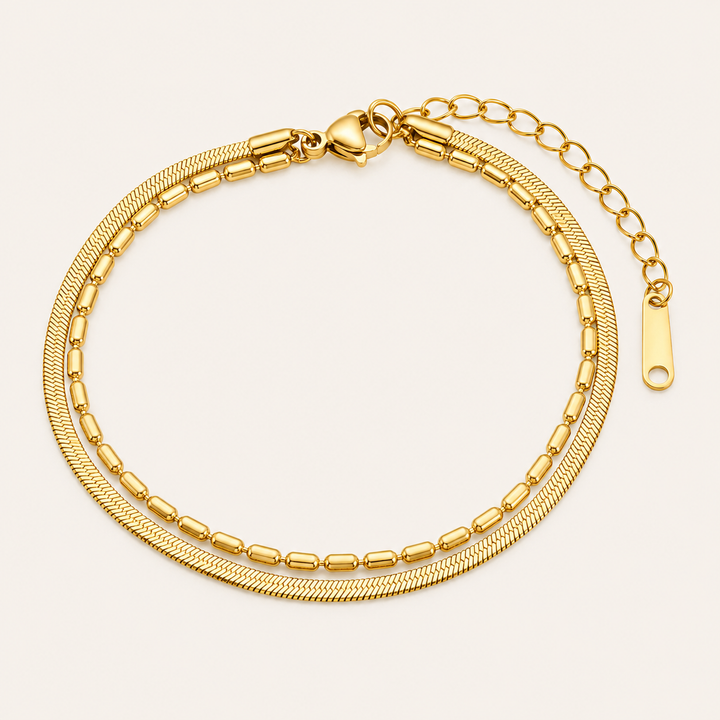 A gold-toned double-layered chain bracelet with a textured herringbone top layer and a beaded bottom layer.