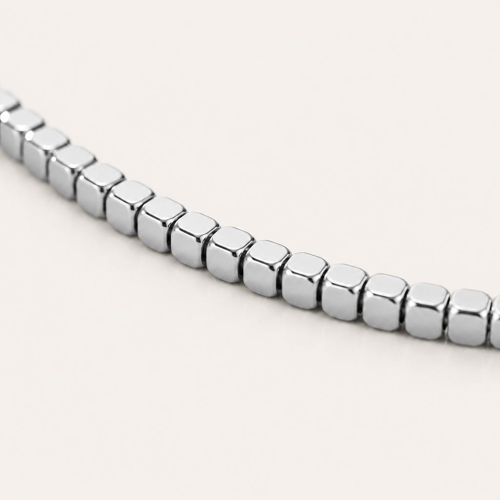 A close-up of a polished silver cube-link anklet.