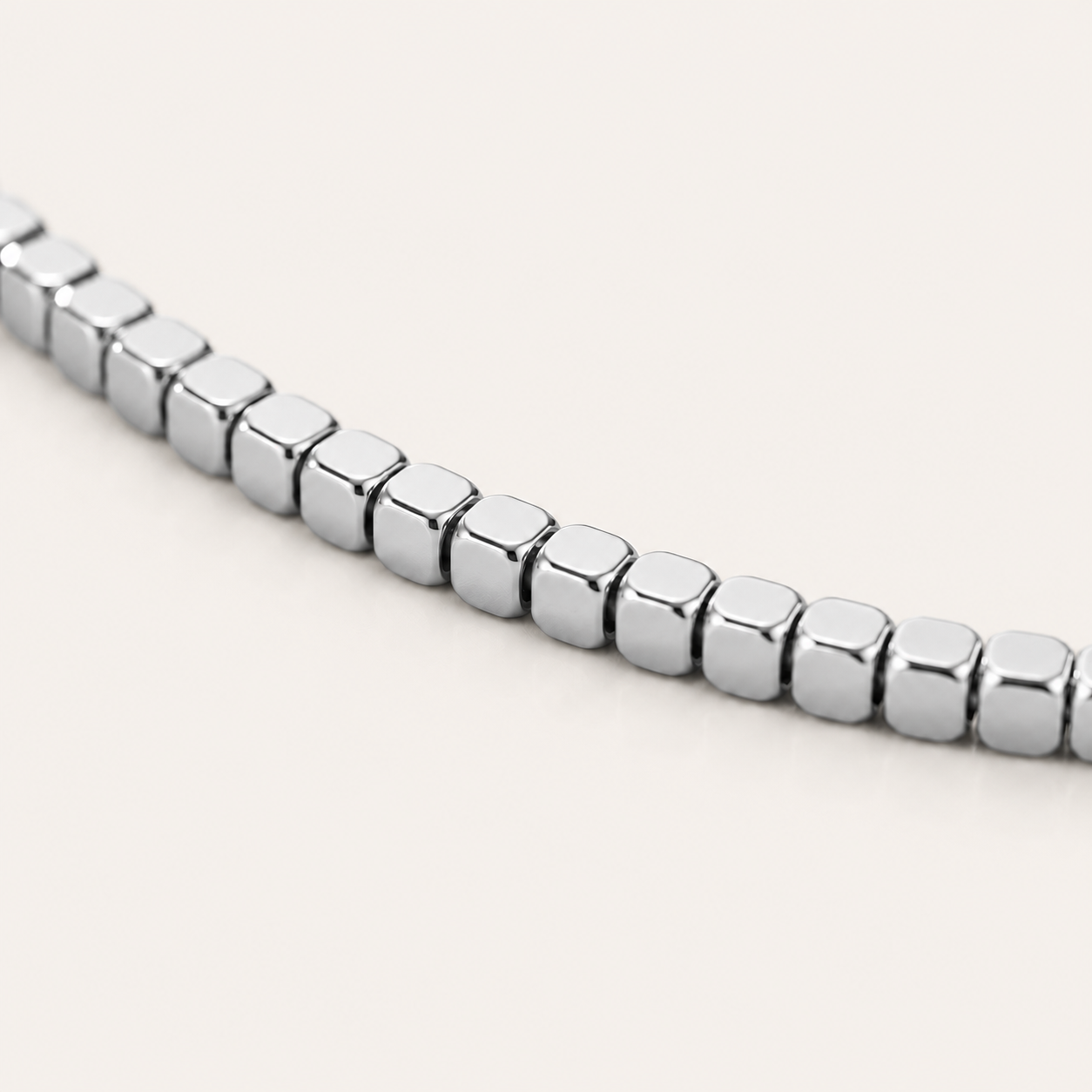 A close-up of a polished silver cube-link anklet.