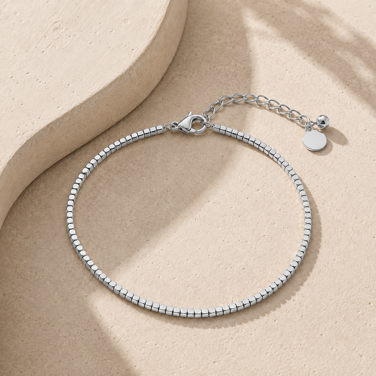 A silver beaded anklet with a lobster clasp and extension chain.