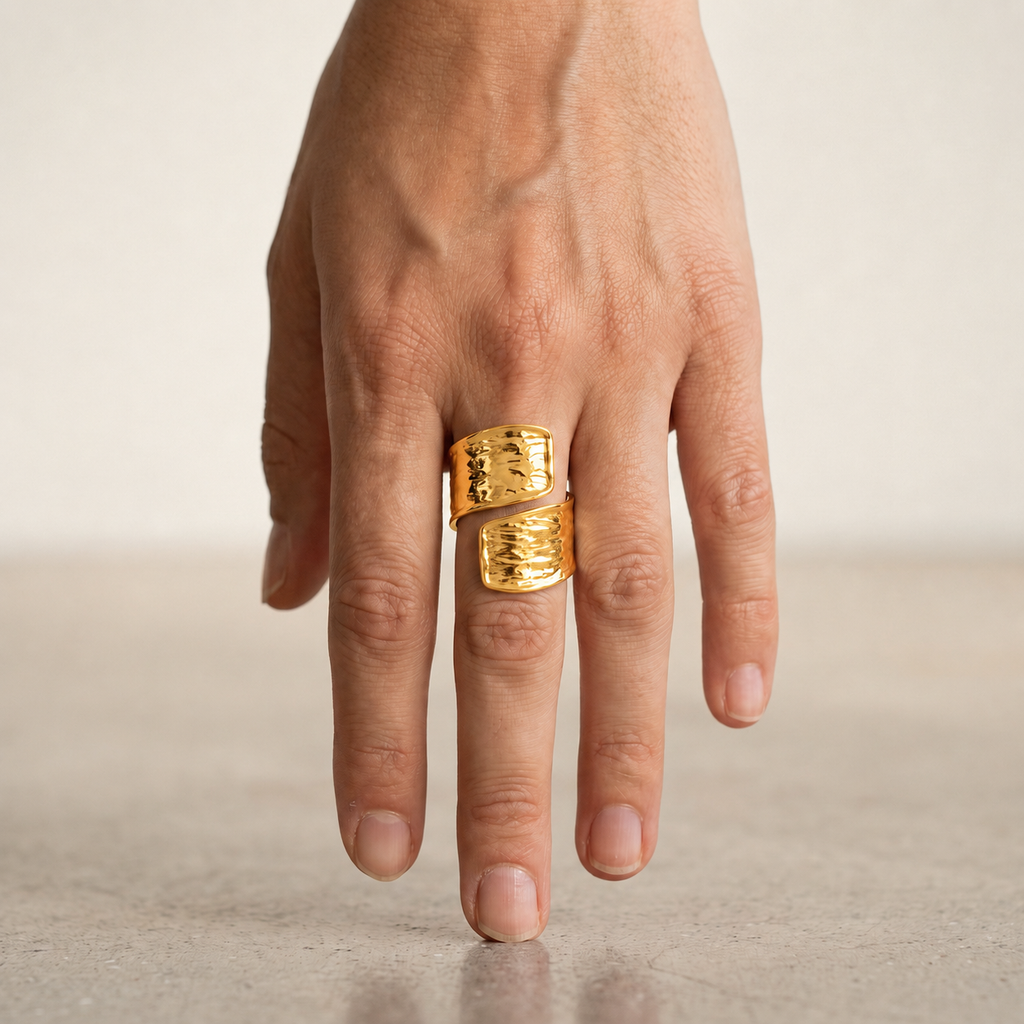 A close-up of a hand wearing a chunky, textured gold ring with two stacked bands.