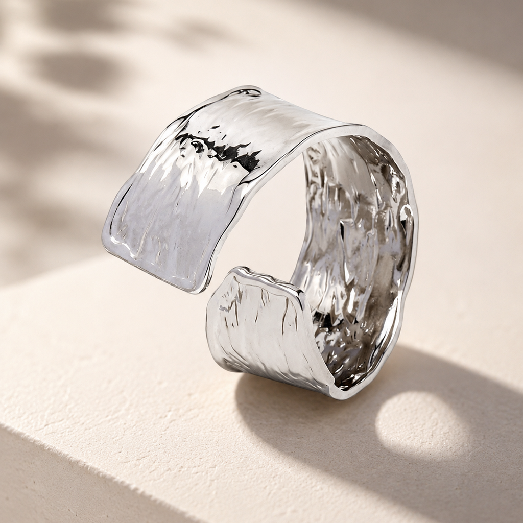 A wide, open cuff ring with a hammered silver finish.