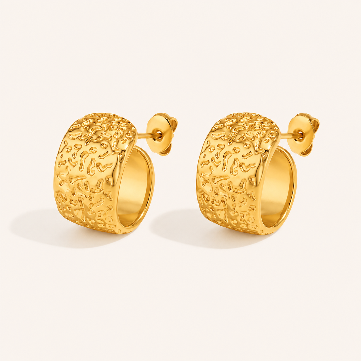 A pair of textured gold huggie hoop earrings with post-back closures.