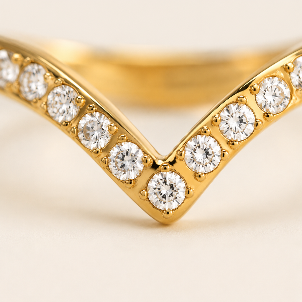A close-up of a gold V-shaped ring set with round-cut clear zircon gemstones.
