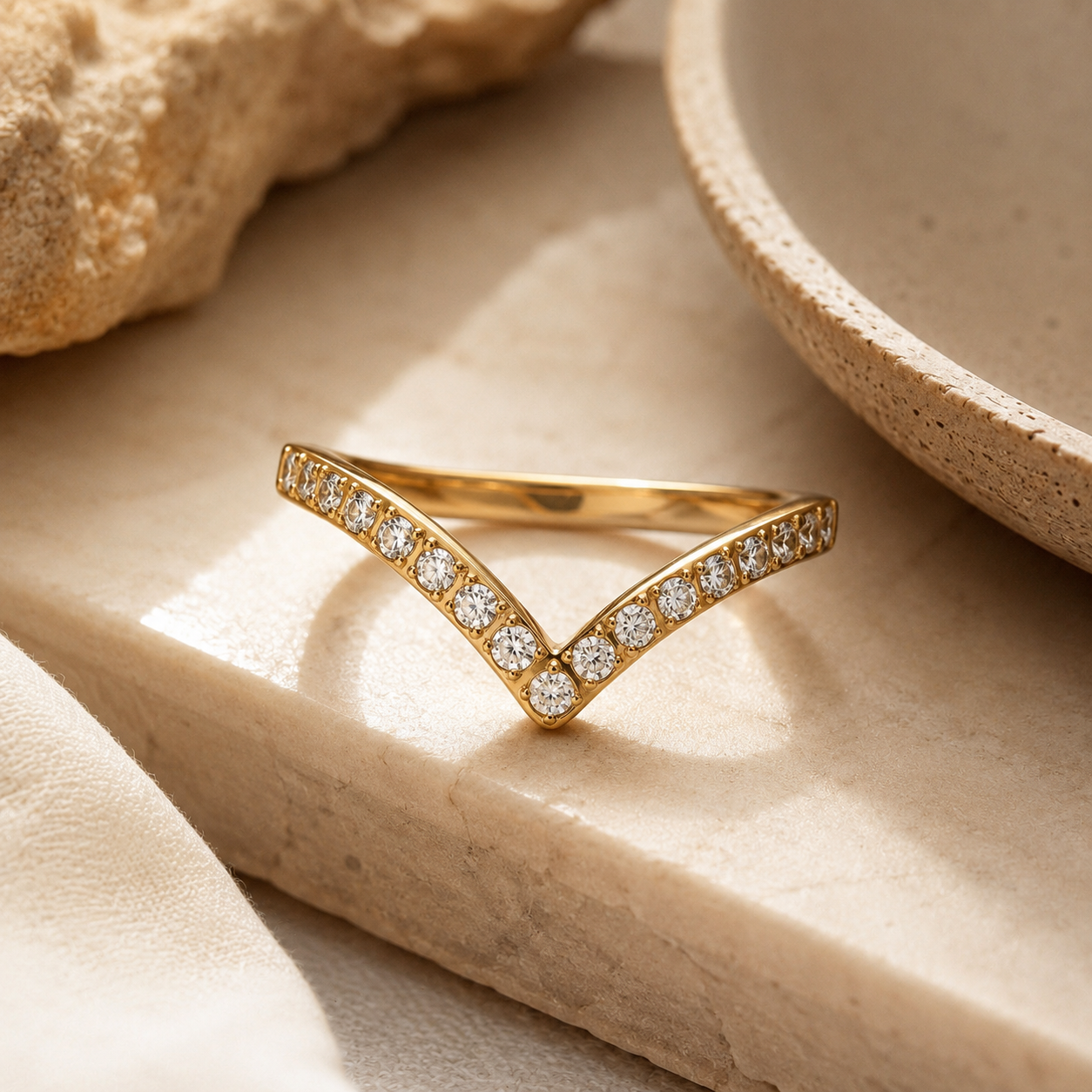A gold V-shaped ring set with small clear zircon stones.