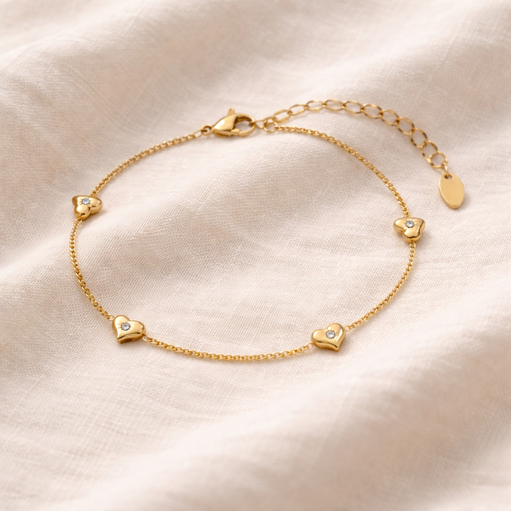 Gold bracelet with heart-shaped charms on a linen fabric background