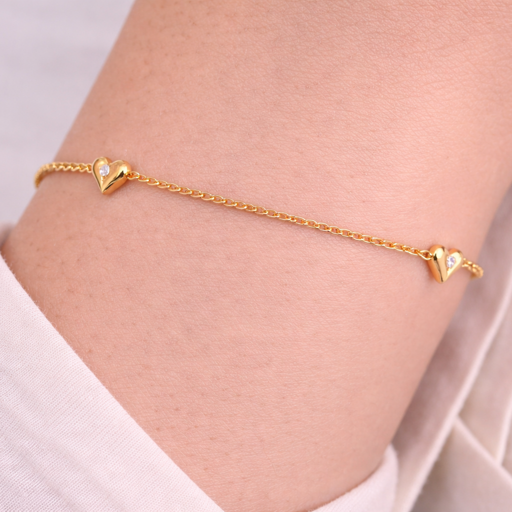 Gold bracelet with hearts shown on a wrist