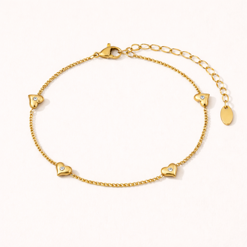 Gold bracelet with heart shaped charms on a soft white background