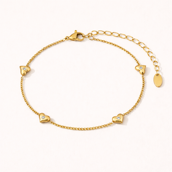 Gold bracelet with heart shaped charms on a soft white background