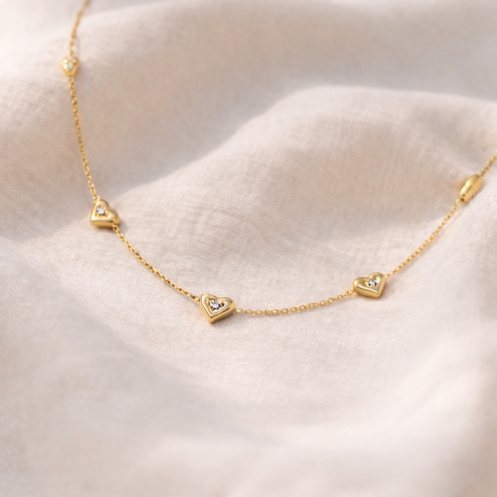 Amora gold necklace laid out on a linen surface