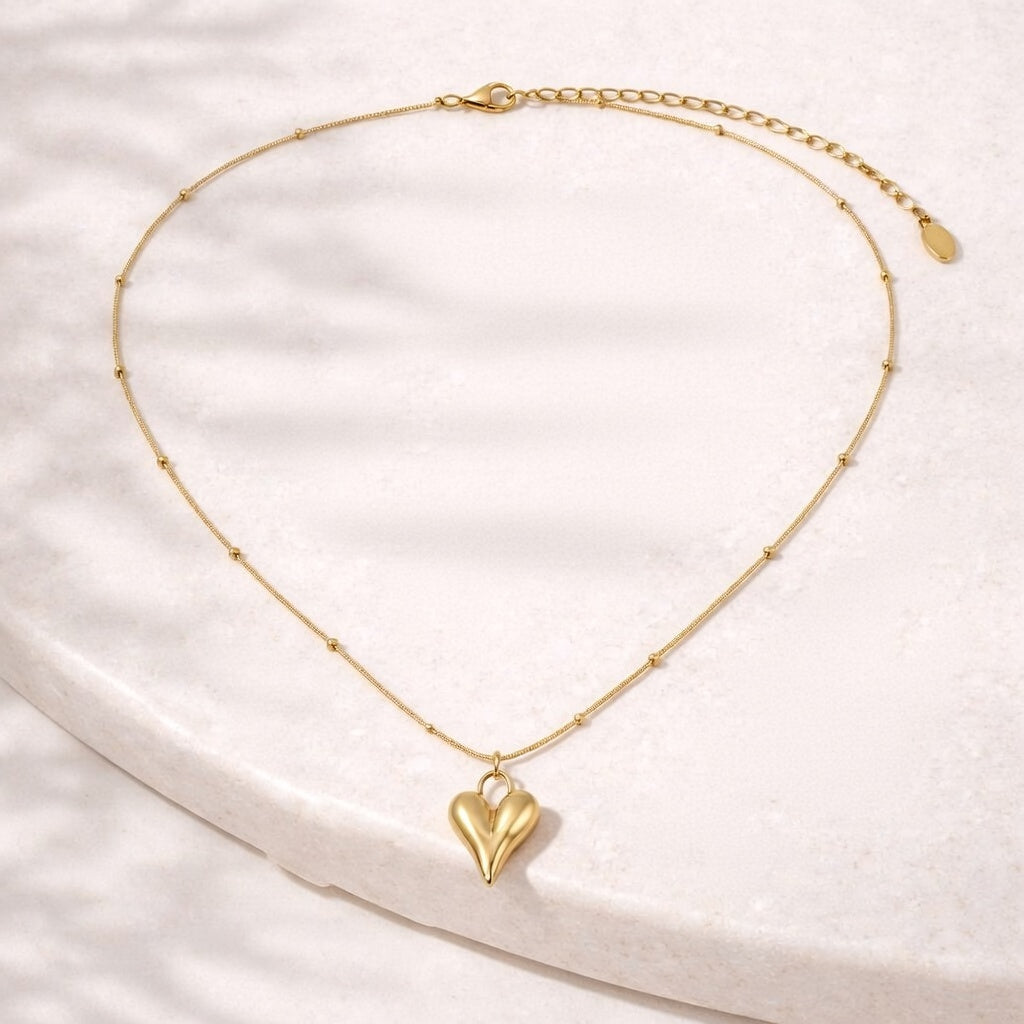 Gold heart-shaped pendant necklace on a light stone background