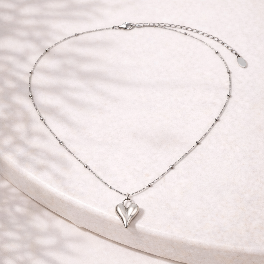 Silver heart-shaped pendant necklace on a light stone background