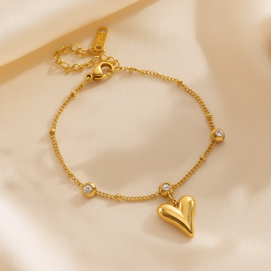 Gold bracelet with a heart charm on a beige background
