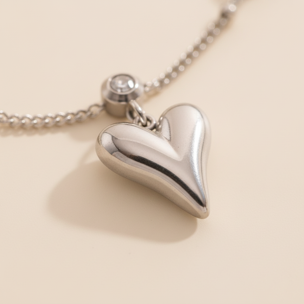Silver heart-shaped pendant on a chain against a beige background