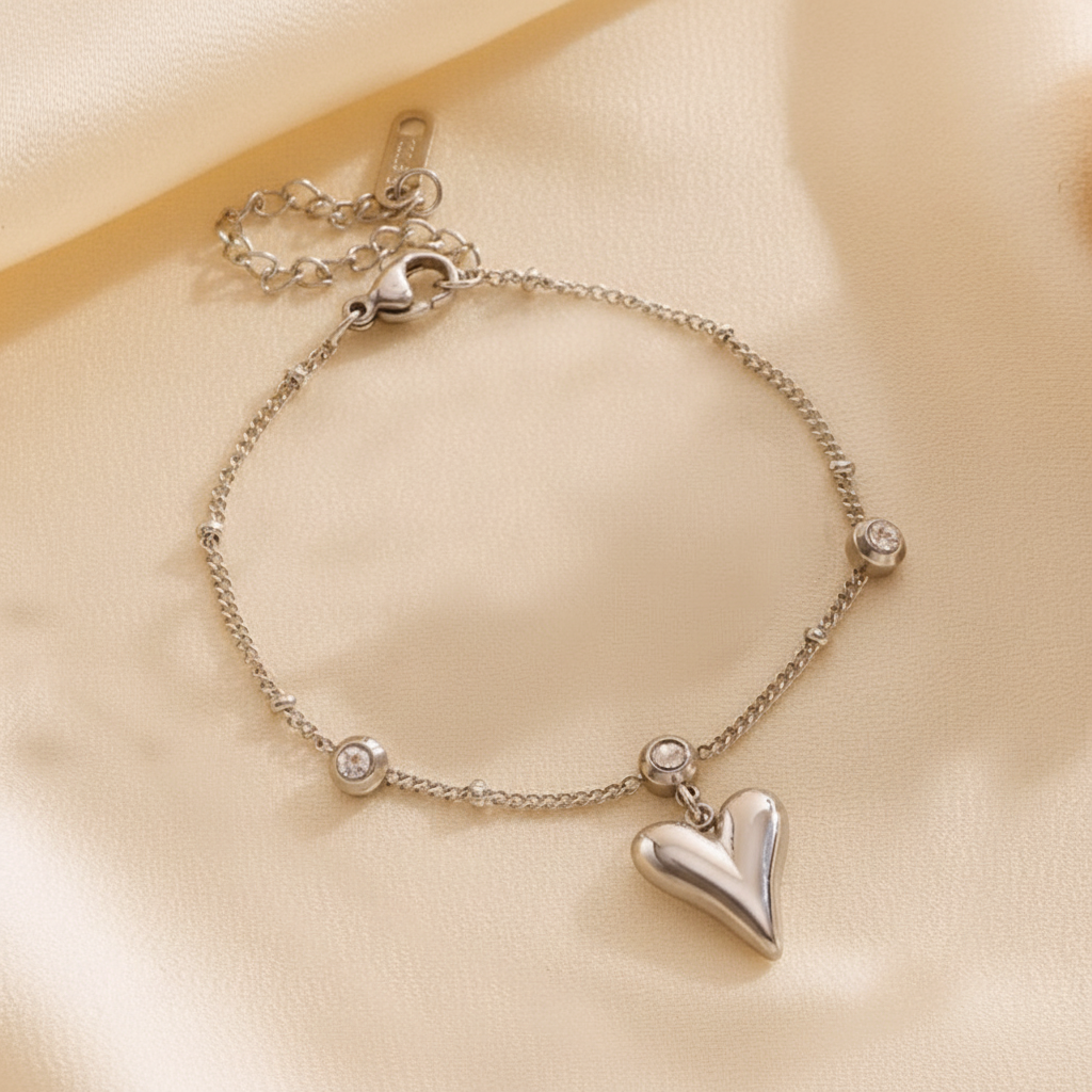 Silver bracelet with heart charm on a beige background