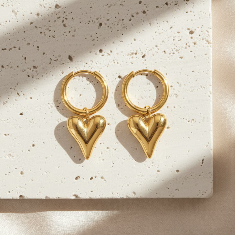 Gold heart-shaped hoop earrings on a textured beige surface