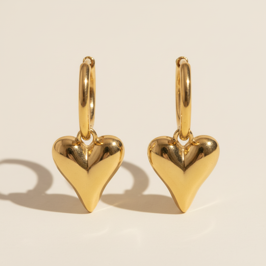 Gold heart-shaped earrings on a beige background