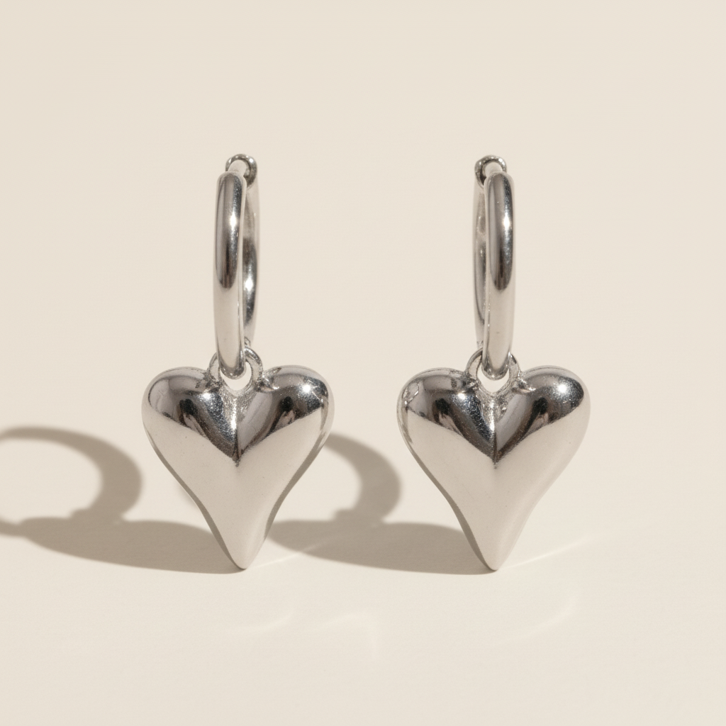 Silver heart-shaped earrings on a beige background