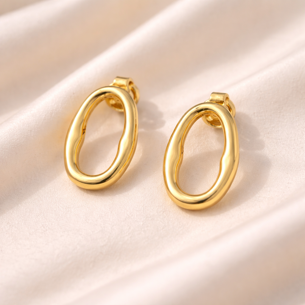 Oval earrings in gold shown on a silk surface