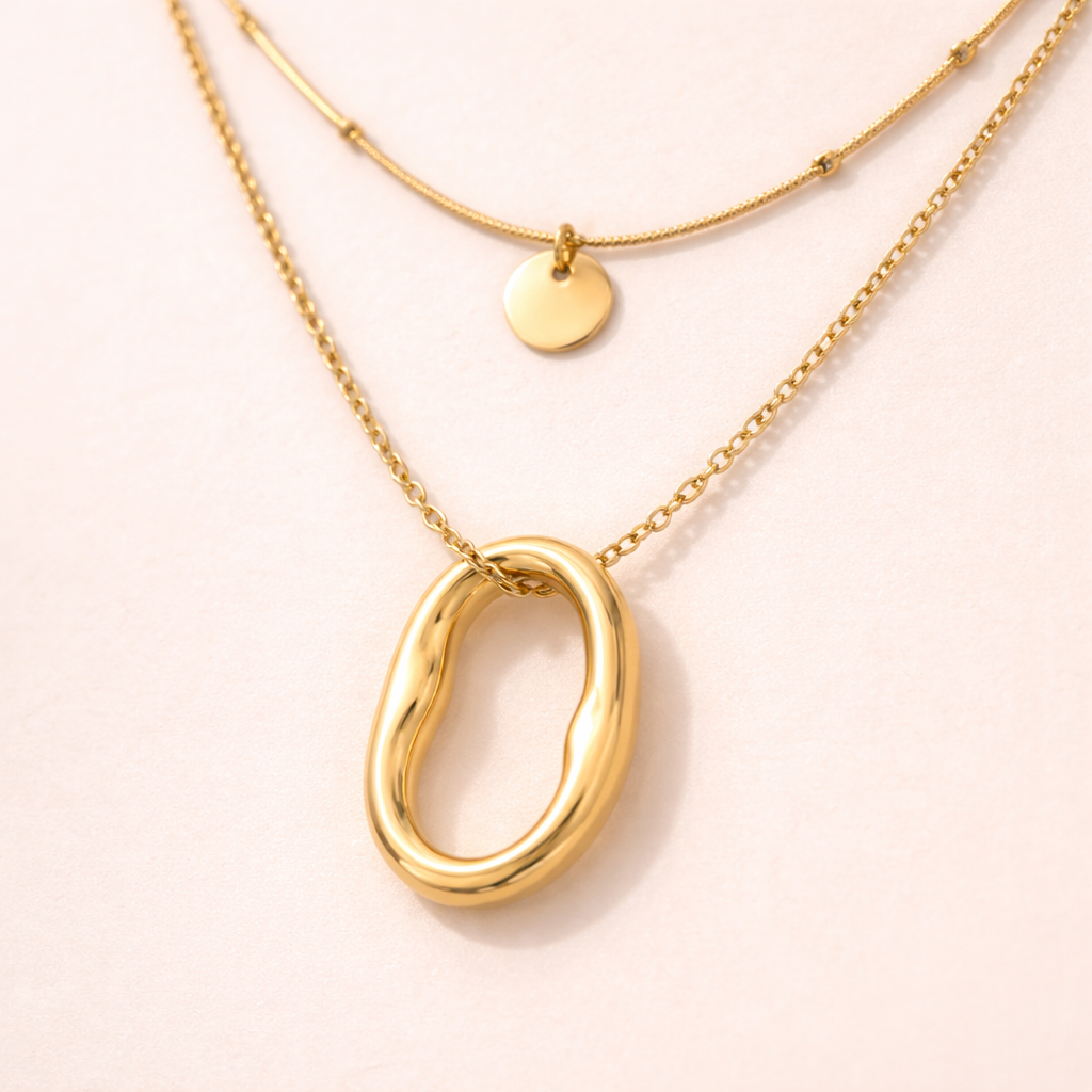 Close-up of oval pendant layered gold necklace