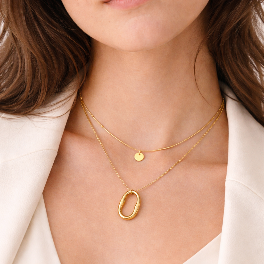 Close shot of model wearing oval pendant layered gold necklace