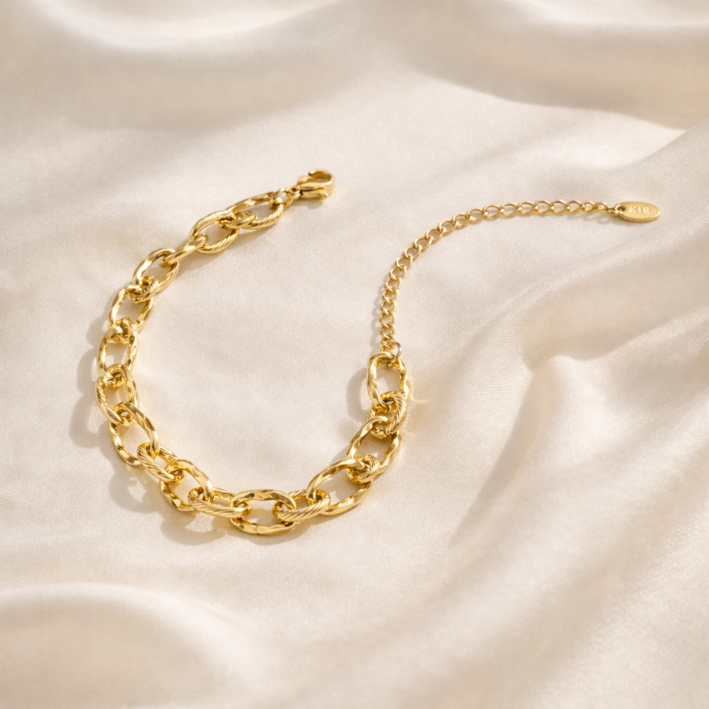 Gold chain bracelet on a beige fabric background