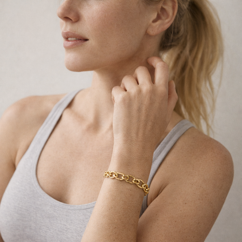Woman wearing a gold bracelet on a neutral background