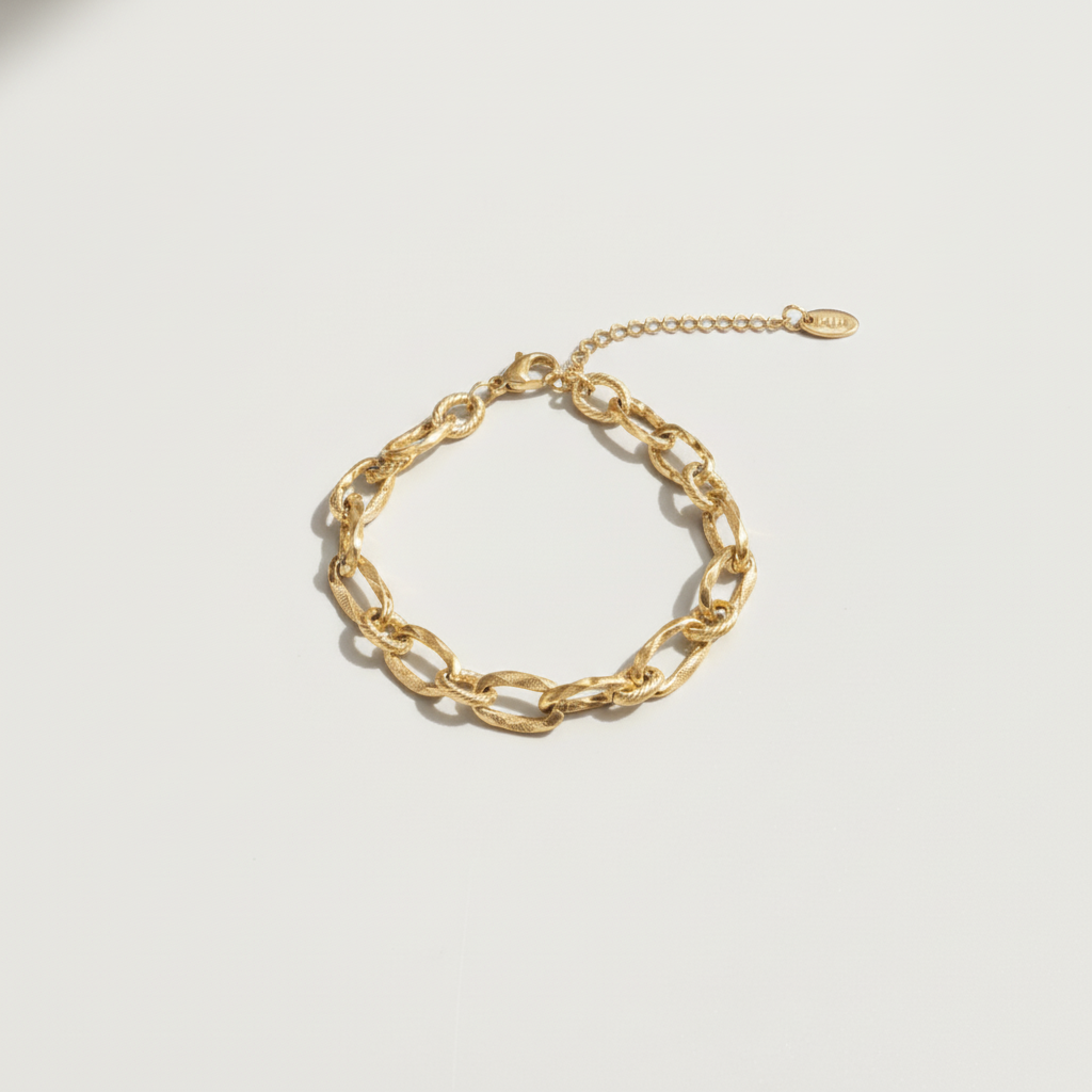 Gold chain bracelet on a light gray background